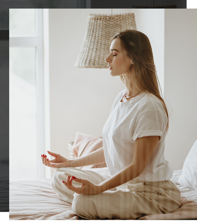 A woman is sitting cross-legged with her hands palms up and resting on her knees in a meditative posture.