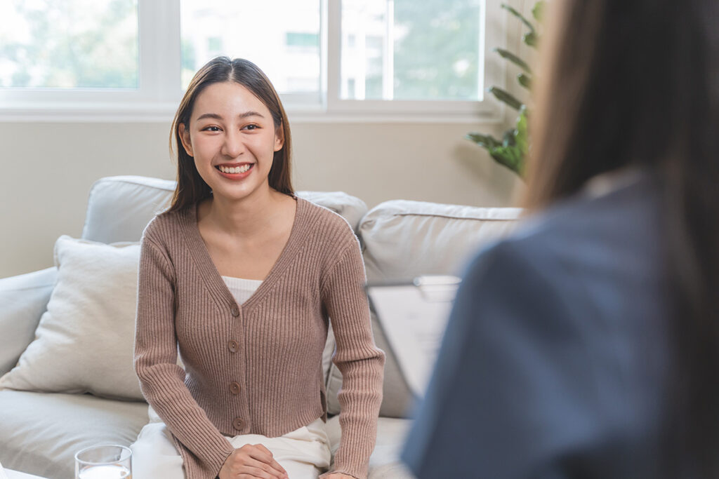 an adolescent client is smiling while speaking with her therapist