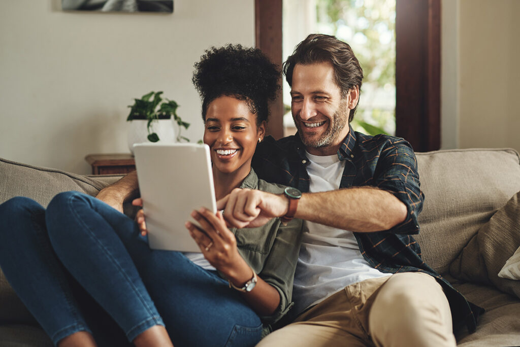A man and woman are snuggled together on a couch and she is holding a tablet in her hands. They are enjoying Elevate Point's intensive outpatient program